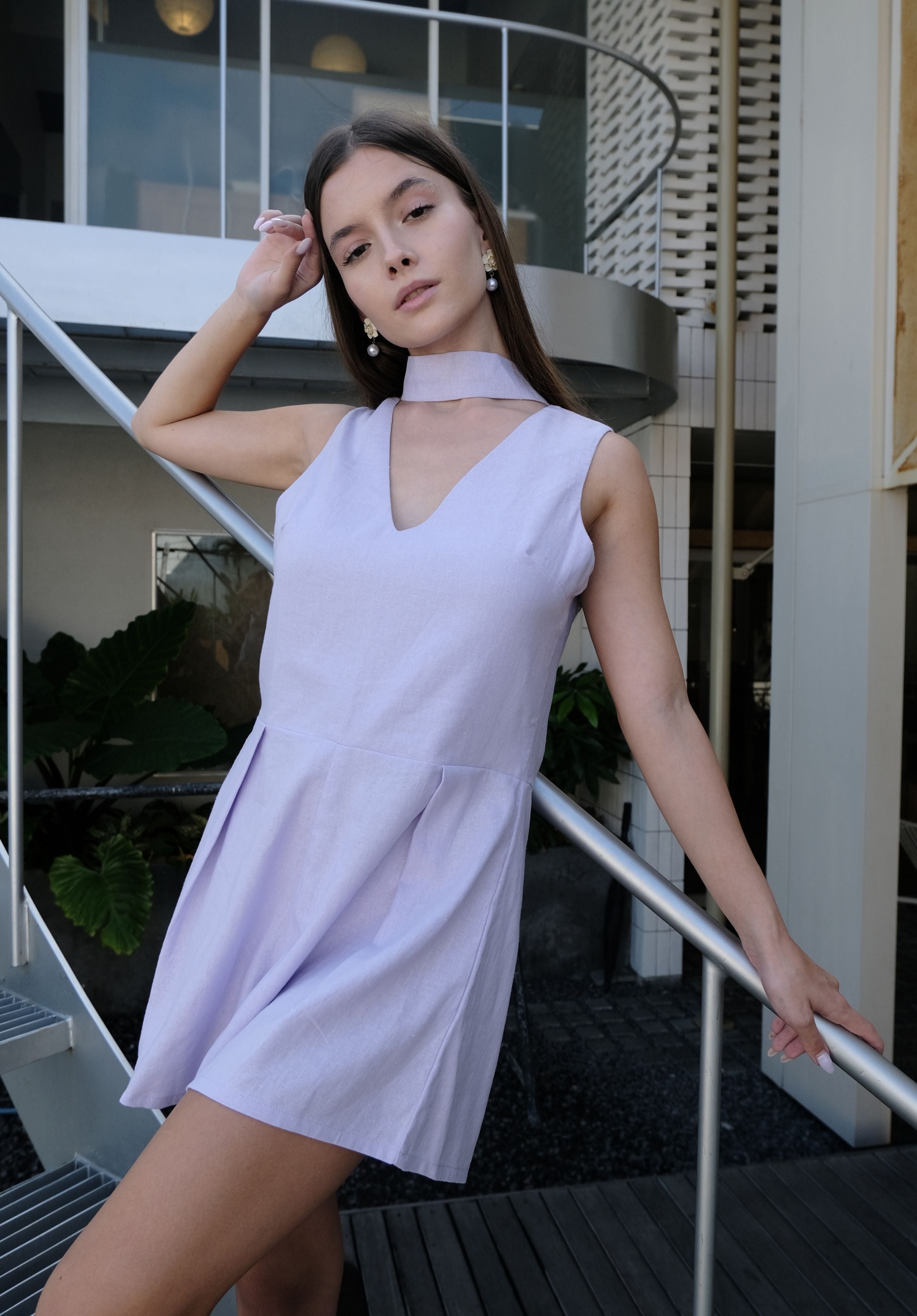 Woman in a light purple dress standing on a balcony.
